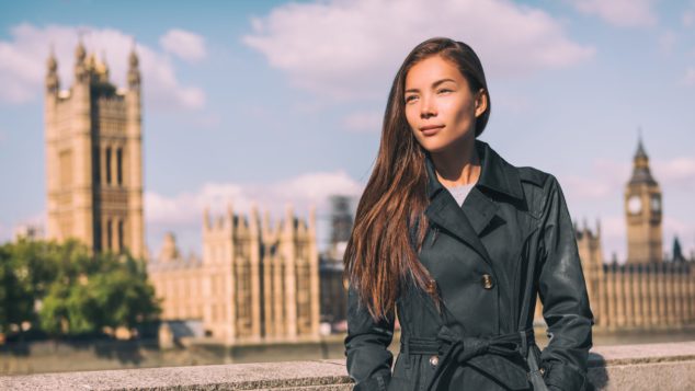  Asian woman standing in front of House of Commons, Westminster Palace, self-employed national insurance concept 